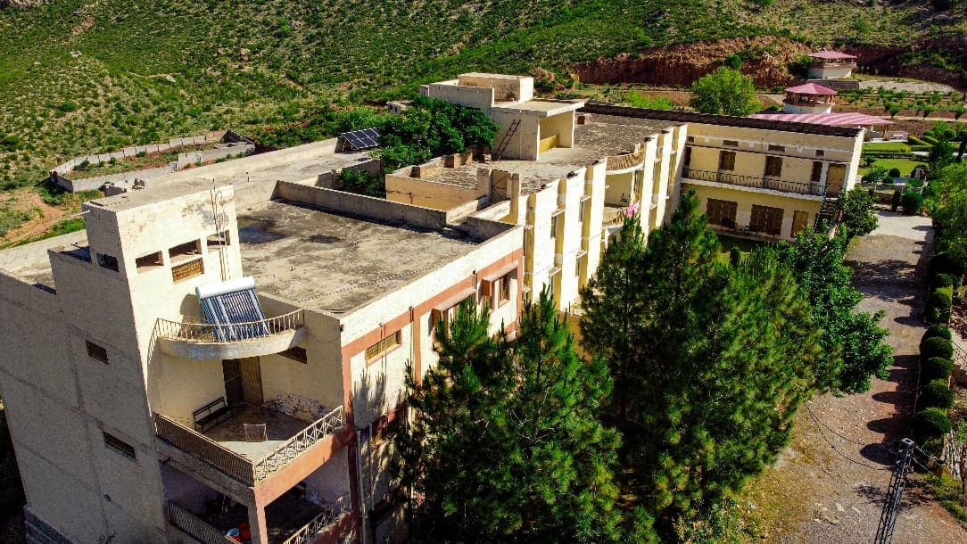 Al-Asar Academy buildings surrounded by pine trees
